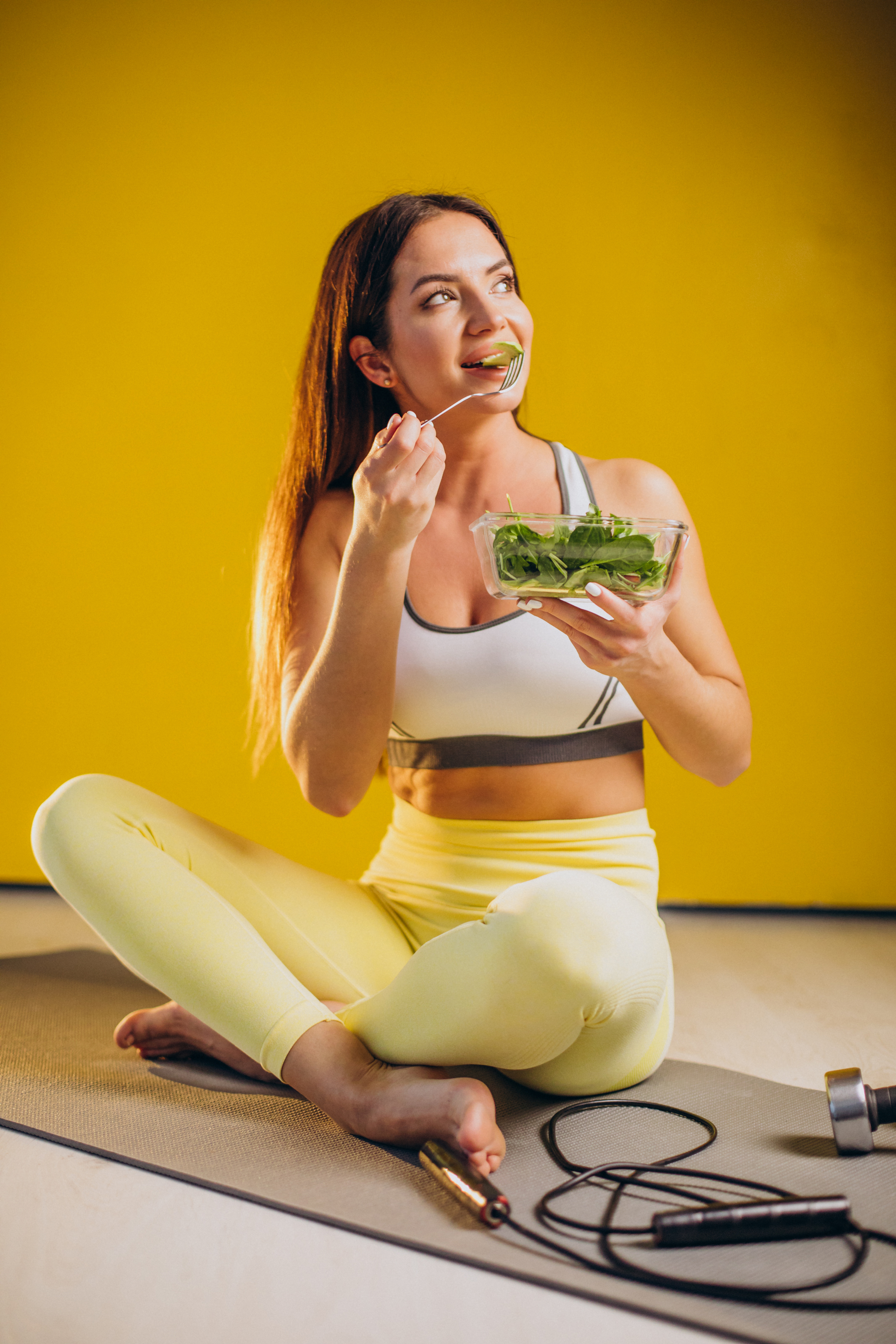 woman-eating-salad-isolated-yellow-background
